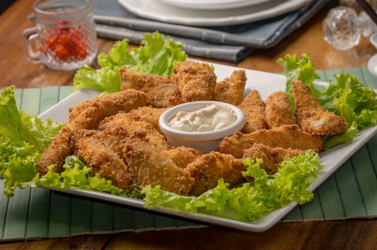 Platter of deep-fried chicken strips with a creamy dip